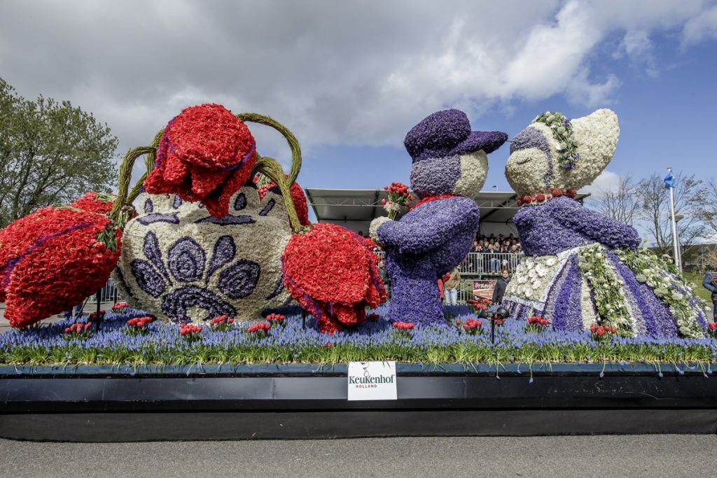 Flower Parade float of a Dutch couple and a Delft-blue vase made of hyacinths and tulips, with a Keukenhof sign